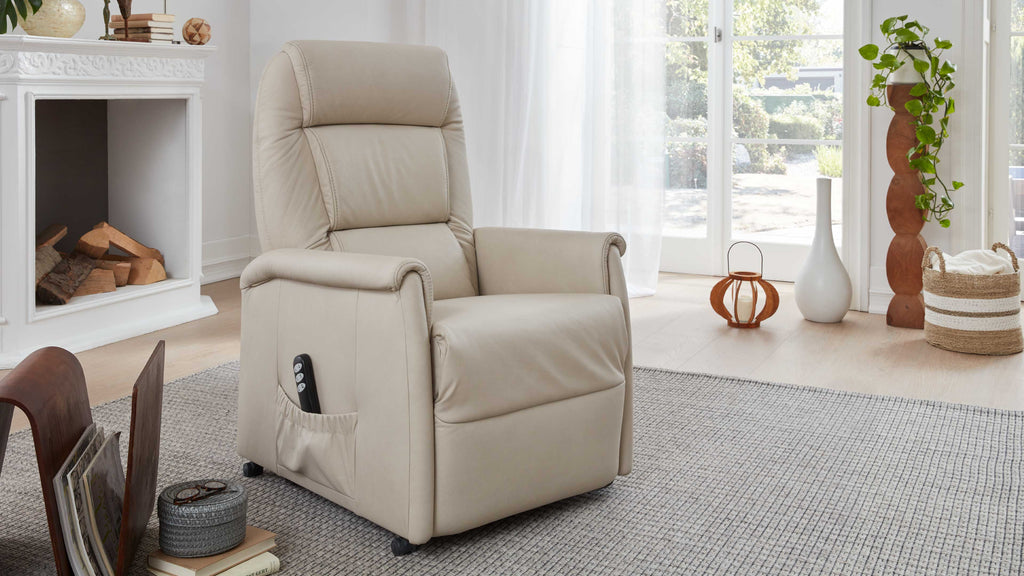 Beige Relaxsessel mit Armlehnen, einfacher Bedienung über Fernbedienung, steht auf einem hellen Teppich in einem lichtdurchfluteten Raum.