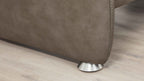 Die untere Ecke eines braunen Sofas mit einer eleganten Metallfüße ist auf einem hellen Holzboden sichtbar.